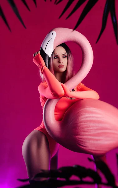 Une fille en body lumineux pose avec une grande figurine Flamingo — Photo
