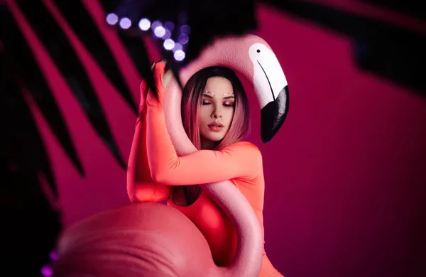 Parlak vücutlu bir kız büyük bir Flamingo heykelciğiyle poz veriyor. — Stok fotoğraf
