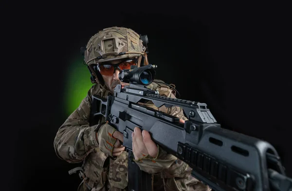 Un soldato maschio in abiti militari con un'arma su sfondo scuro — Foto Stock