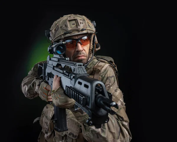 Egy férfi katona katonai ruhában, fegyverrel a sötét hátterében. — Stock Fotó