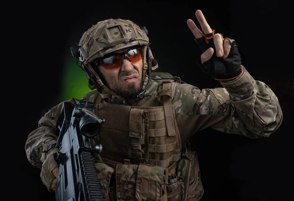 A male soldier in military clothes with a weapon on a dark background — Stock Photo, Image