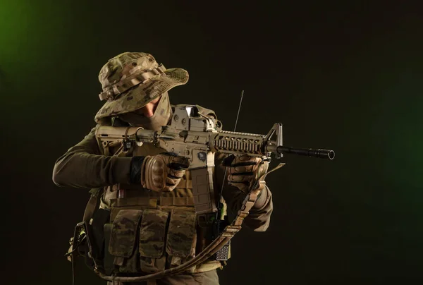 Voják-sabotér ve vojenském oblečení se zbraněmi na tmavém pozadí — Stock fotografie