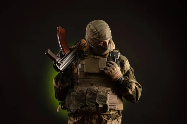 Soldier militia saboteur in military clothing with a Kalashnikov rifle on a dark background — Stock fotografie