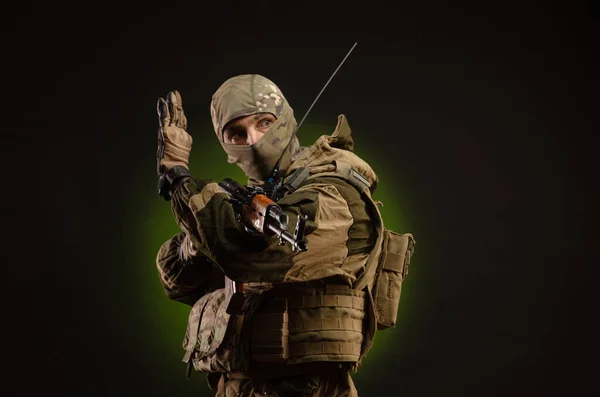 Ein Saboteursoldat in Militärkleidung mit Waffe auf dunklem Hintergrund zeigt Gesten — Stockfoto