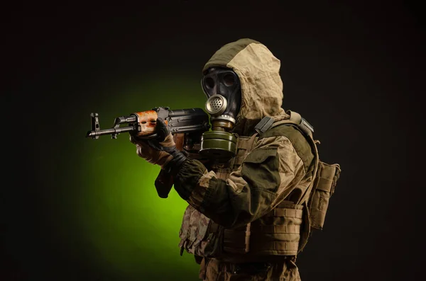 Soldat Stalker sabotör i militär uniform med en Kalashnikov gevär på en mörk bakgrund i en gasmask — Stockfoto