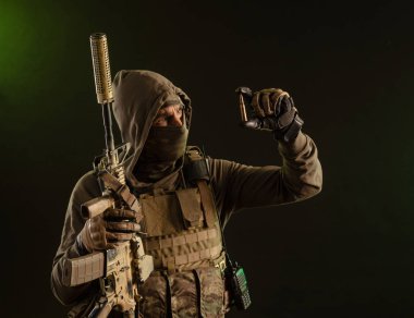 a soldier-saboteur in military uniform with a weapon on a dark background shows a bullet
