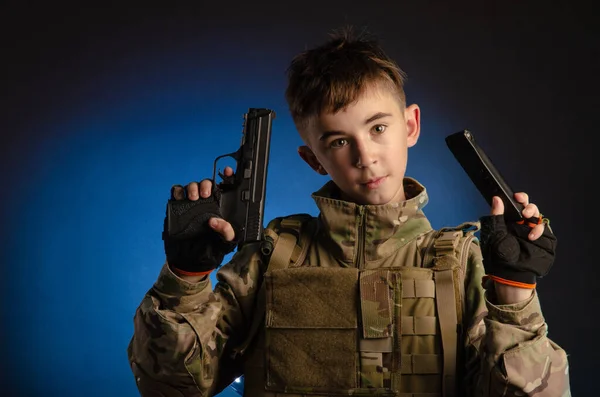 Um rapaz de uniforme militar com uma arma — Fotografia de Stock