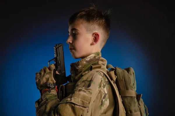 A boy in military uniform with a gun — Stockfoto