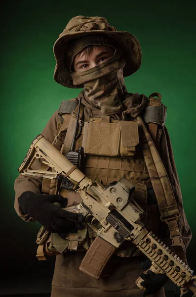 A boy in military uniform with a gun — Stok fotoğraf