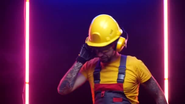 Un trabajador de la construcción en un sombrero duro escucha música — Vídeo de stock