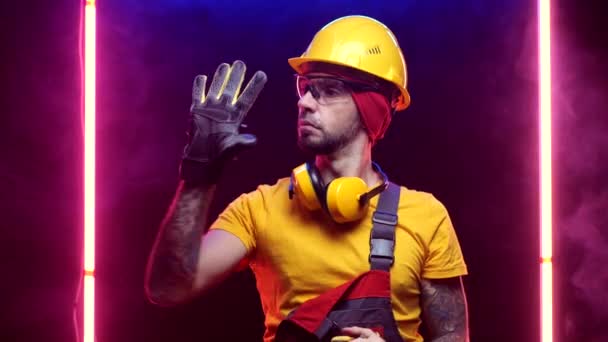 Un trabajador de la construcción con un sombrero duro se pone guantes — Vídeos de Stock