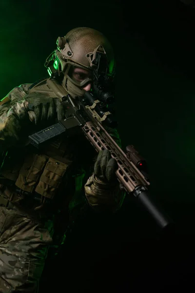 Un soldato in abiti militari con un dispositivo di visione notturna e su uno sfondo scuro — Foto Stock