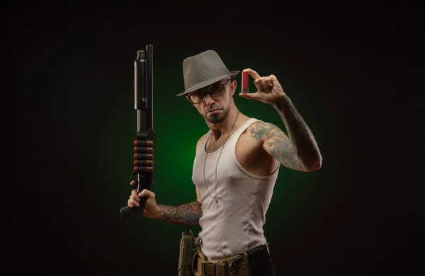 Un sportif avec un tatouage pose avec un fusil de chasse — Photo