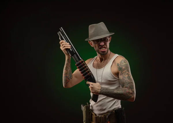 En atletisk kille med en tatuering poserar med ett hagelgevär — Stockfoto