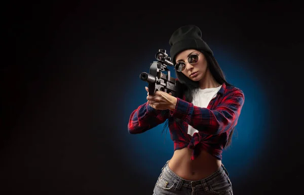 Dziewczyna w sprawdzonej koszuli na ciemnym tle ze strzelbą — Zdjęcie stockowe