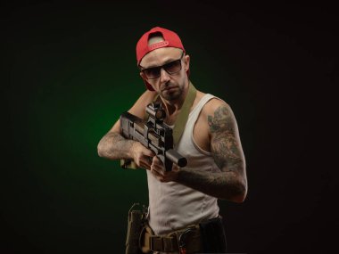 Dövmeli bir sporcu pompalı tüfekle poz veriyor.