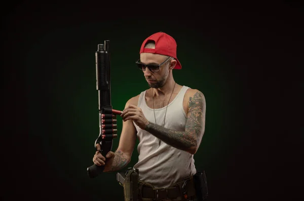 Un sportif avec un tatouage pose avec un fusil de chasse — Photo
