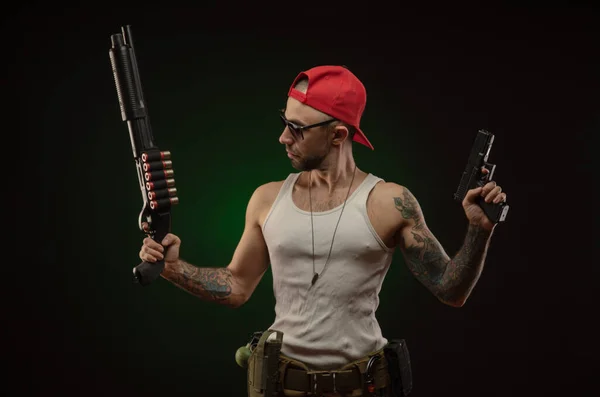 Un sportif avec un tatouage pose avec un fusil de chasse — Photo