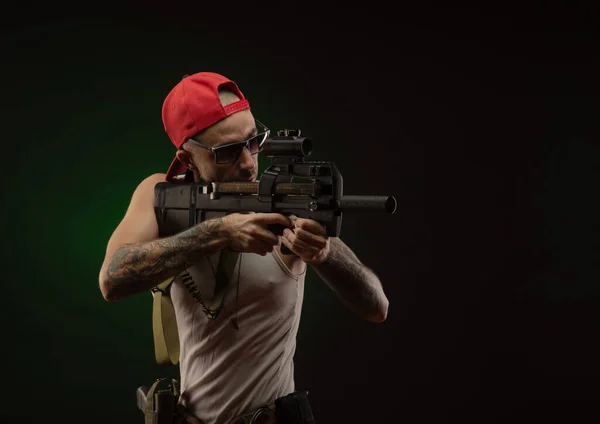 An athletic guy with a tattoo poses with a shotgun — Stock Photo, Image