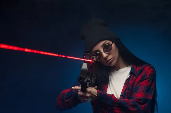 Uma menina em uma camisa marcada em um fundo escuro com um rifle automático — Fotografia de Stock