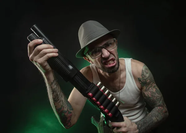 Un sportif avec un tatouage pose avec un fusil de chasse — Photo