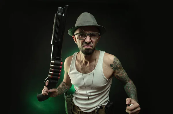 Een atletische kerel met een tatoeage poseert met een shotgun — Stockfoto