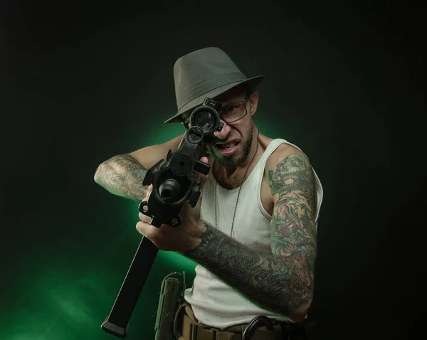 Un sportif avec un tatouage pose avec un fusil automatique — Photo