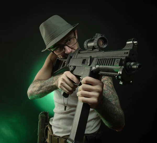 Un sportif avec un tatouage pose avec un fusil automatique — Photo