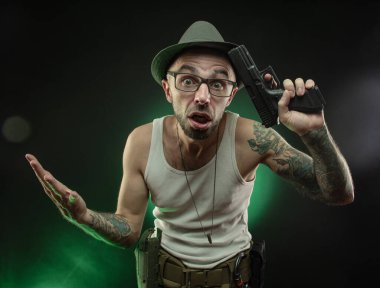 Dövmeli bir sporcu tabancayla poz veriyor.