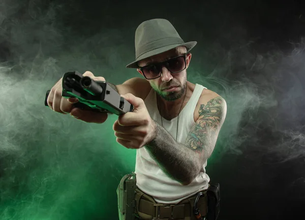 Wysportowany facet z tatuażem pozuje pistoletem — Zdjęcie stockowe