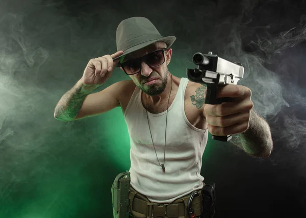 Een atletische kerel met een tatoeage poseert met een pistool — Stockfoto
