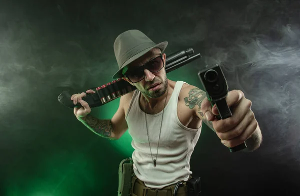 Un sportif avec un tatouage pose avec un fusil de chasse — Photo