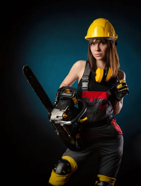 Menina de macacão com uma motosserra — Fotografia de Stock