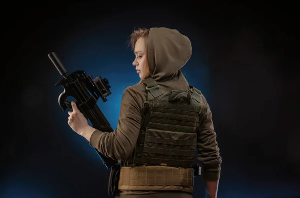A lány katonai overálban Airsoft pózol egy pisztollyal a kezében egy sötét háttérben — Stock Fotó
