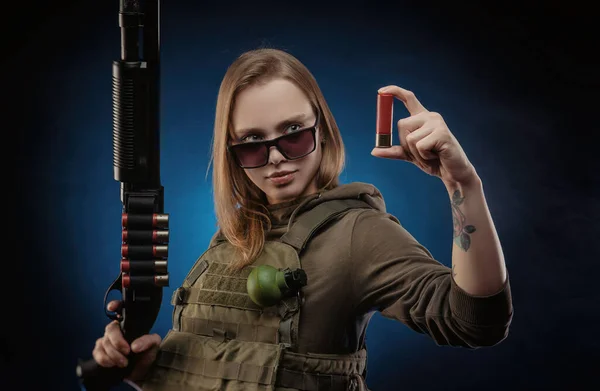 La jeune fille en salopette militaire airsoft posant avec un pistolet dans ses mains sur un fond sombre — Photo