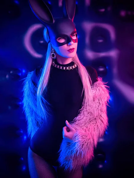 Sexy ragazza in un body e pelliccia con una maschera di coniglio nella luce al neon — Foto Stock
