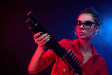 Parlak esmer, kırmızı tulumlu, siyah arka planda bir av tüfeği var.