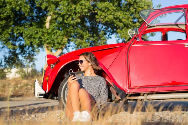 Jonge vrouw rusten op auto — Stockfoto