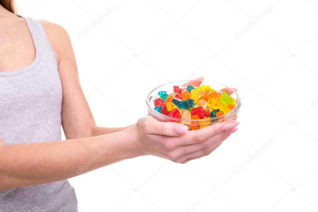Closeup of young woman hands holding bowl of jelly gummy bears, isolated over white background