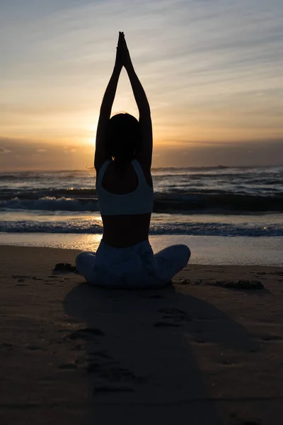 健康的な生活と精神的な開発と体の自然なバランスの概念をビーチでのヨガの練習を行うスポーティな若い女性のシルエット ストックフォト
