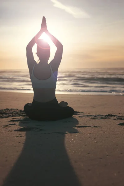 健康的な生活と精神的な開発と体の自然なバランスの概念をビーチでのヨガの練習を行うスポーティな若い女性のシルエット — ストック写真