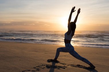 Plaj, sağlıklı yaşam ve beden ve ruhsal gelişimi arasında doğal denge kavramı, yoga pratik yapıyor sportif genç kadın silüeti