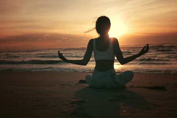 运动的年轻妇女在海滩做瑜伽练习 健康生活的概念和身体与精神发展之间的自然平衡 — 图库照片