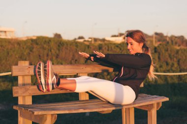Genç, güzel Çinli kadın gün doğumunda sahilde egzersiz yapıyor. 