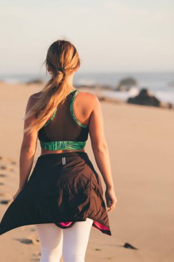 Genç, güzel Çinli kadın gün doğumunda ve günbatımında sahilde egzersiz yapıyor.