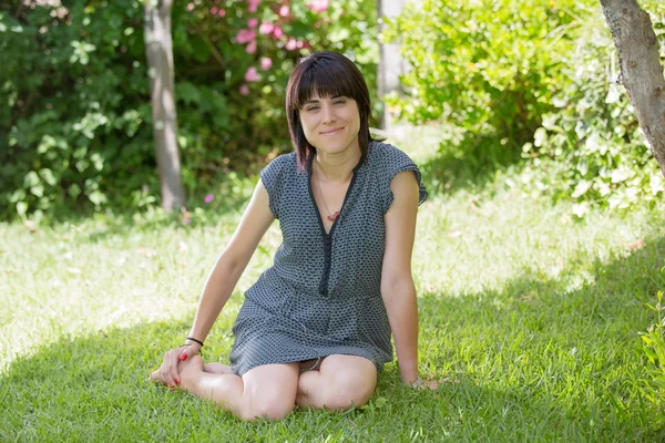 Giovane donna casual posa seduta, sorridente alla macchina fotografica, all'aperto — Foto Stock