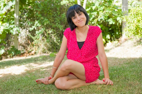 Junge lässige Frau posiert im Sitzen, lächelt in die Kamera, im Freien — Stockfoto