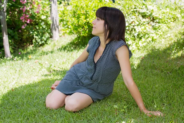 Jovem mulher casual posando sentado, sorrindo, ao ar livre — Fotografia de Stock