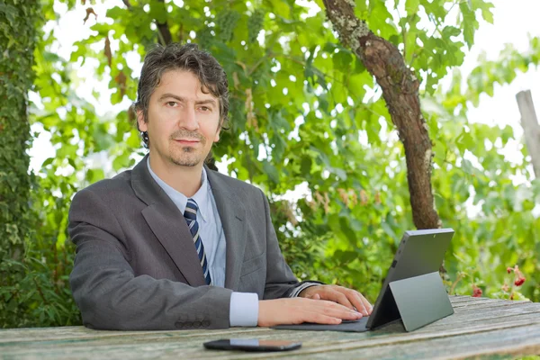 Бизнесмен работает с цифровыми планшетами, на открытом воздухе — стоковое фото