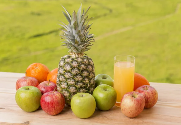 Glas apelsinjuice och massor av frukt på träbord utomhus — Stockfoto